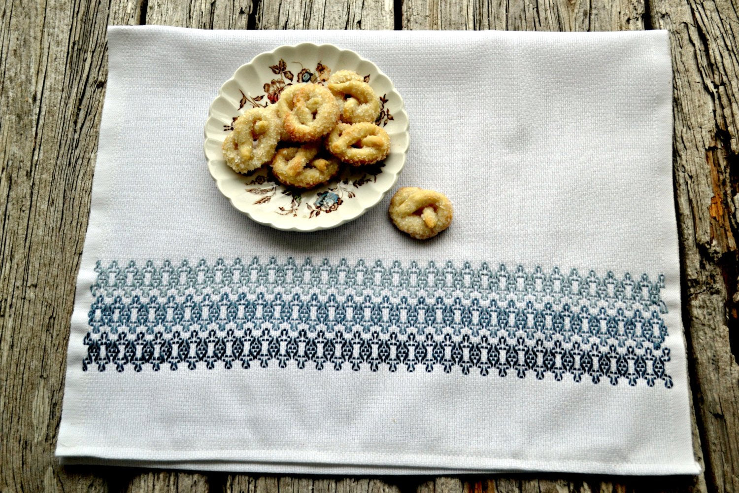Kitchen dish towel embroidered in hazy blues with plate of sugar pretzels
