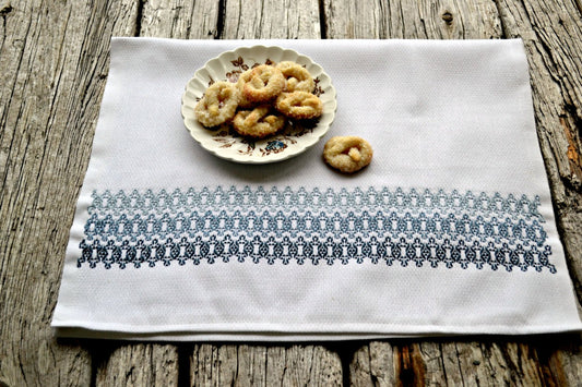 Huckaback tea towel embroidered in soft blues with dish of cookies