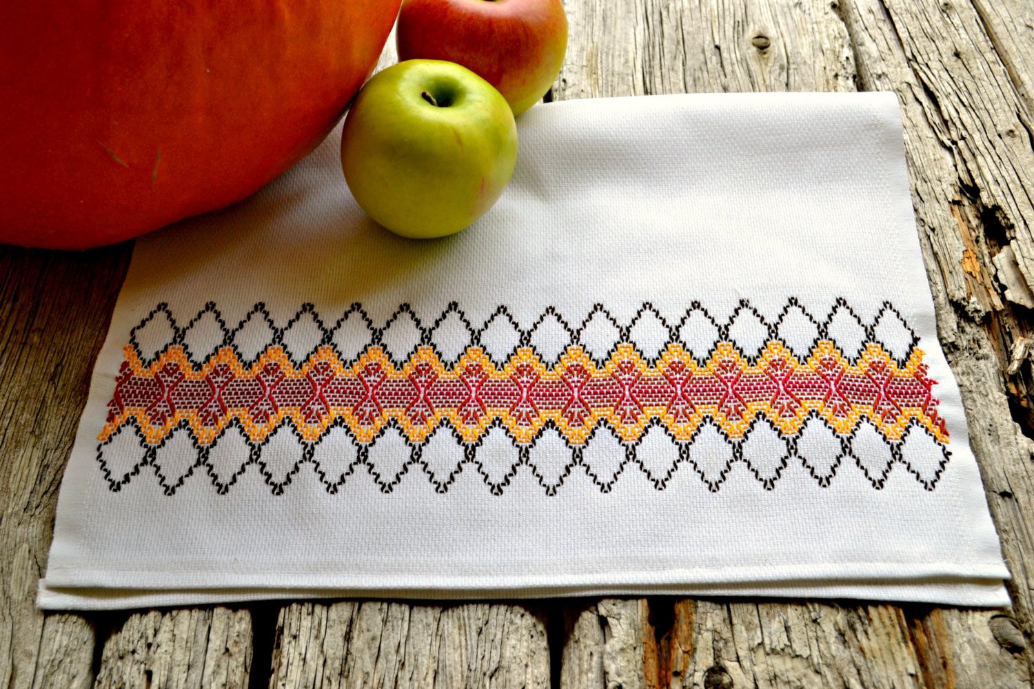 Tea towel decorated with a band of embroidery in autumnal colors