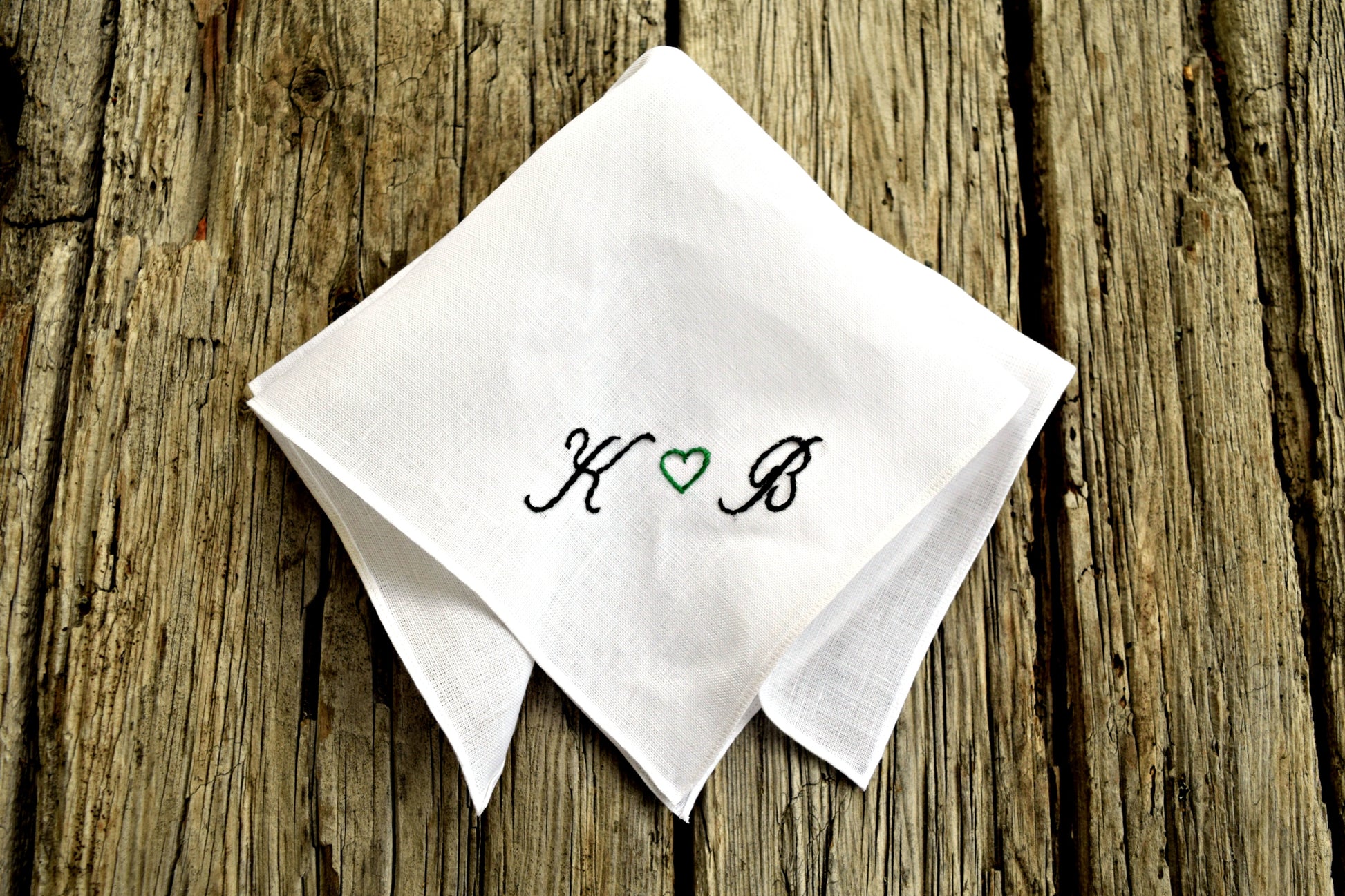 Folded Irish linen handkerchief embroidered with initials on wood ground