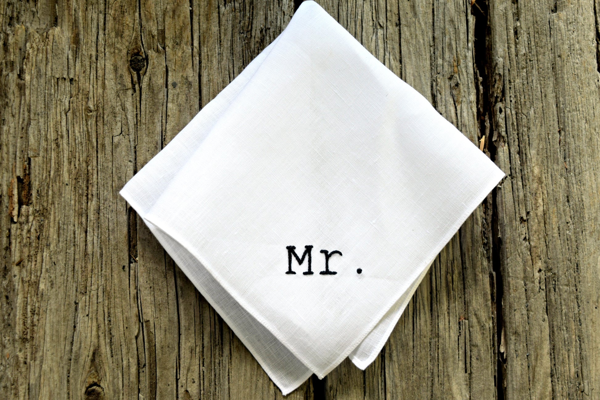 New groom handkerchief embroidered Mr. in block typewriter font in black on wood background