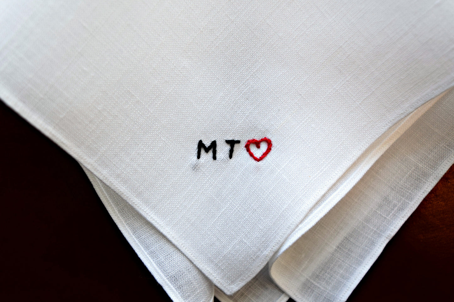 Closeup of handkerchief showing tiny block initials MT and red heart