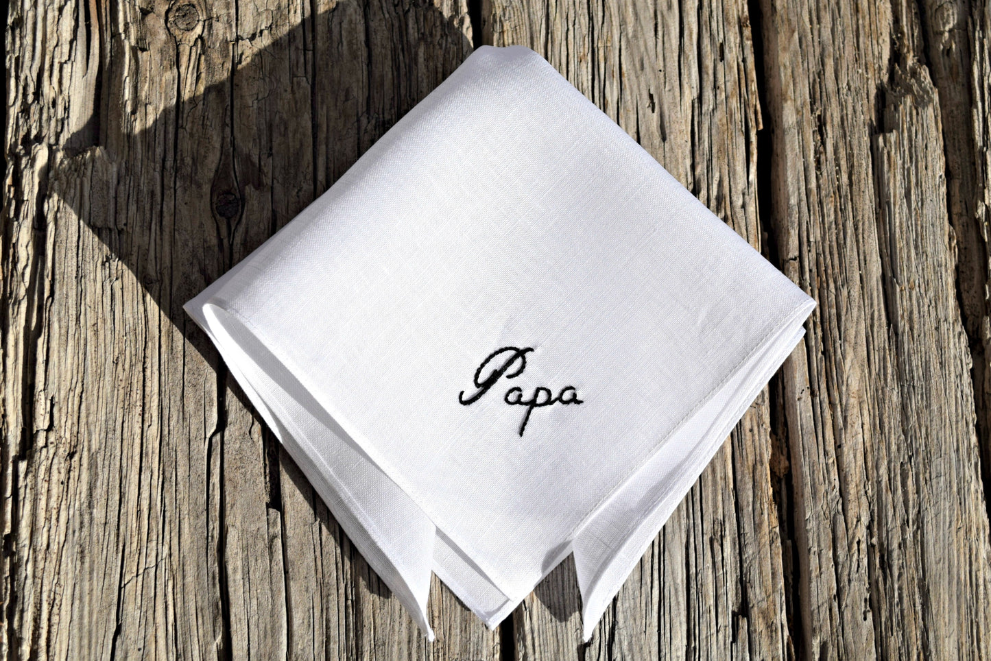 White linen hankie on wood ground, monogrammed with 'Papa'