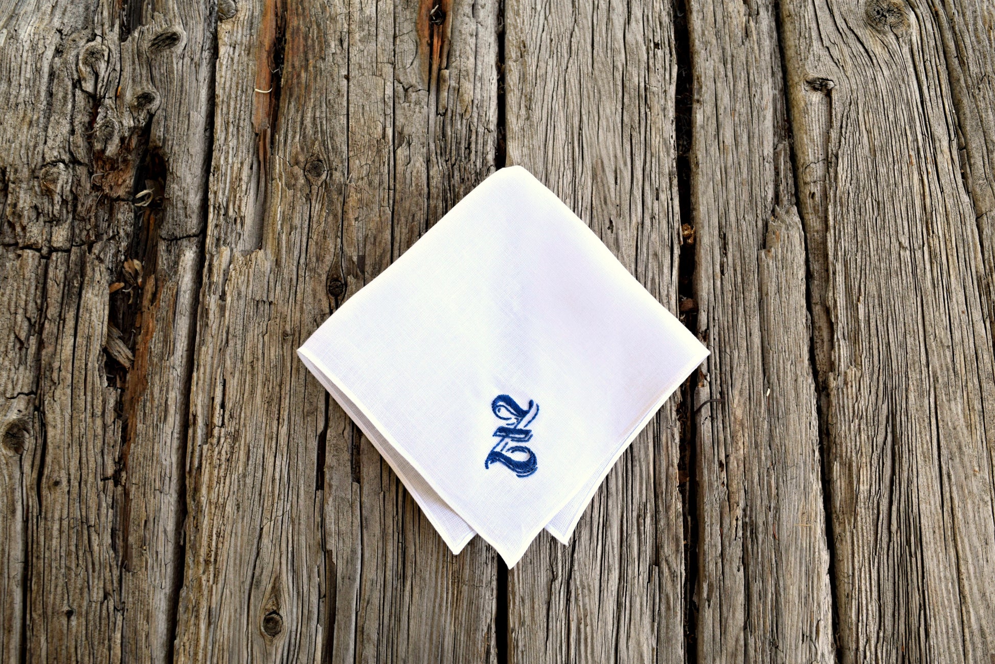 Z hand embroidered on white irish linen handkerchief on wood background